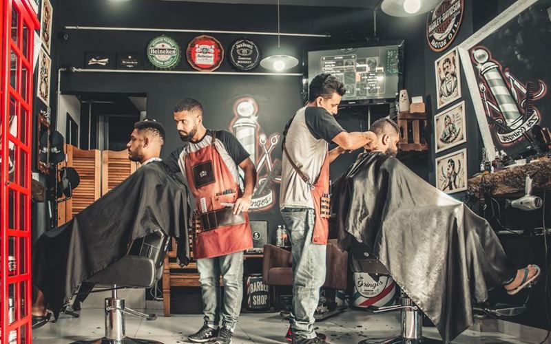 Barbería con dos barberos atendiendo clientes